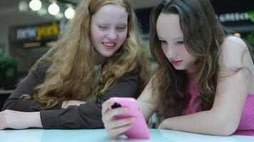 Close up of two young girls looking at smartphone playing mobile games, chatting in social media video