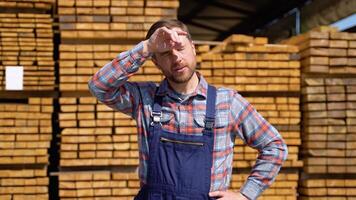 Tired young male worker in timber lumber warehouse video