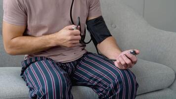 Closeup of unrecognizable male patient using modern tonometer at home. Cropped of middle-eastern man measuring his blood pressure, making self checkup video