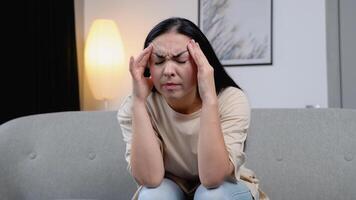 Young woman having a headache at home on sofa video