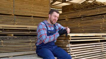 Young male worker in timber lumber warehouse. Concept - sale of lumber video