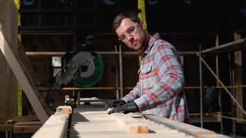 Building contractor worker using hand held worm drive circular saw to cut boards on a new home constructiion project. Modular prefabricated houses concept video