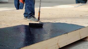 Applying hot resin to the floor for waterproofing, roller and bucket of resin, black and liquid resin. Modular prefabricated houses concept video