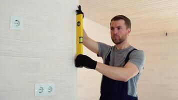 byggare åtgärder av de vertikal avvikelse av de vägg i trä- Hem. bubbla nivå linjal stänga upp se, mätning och utjämning begrepp video