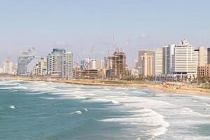 Panoramic View of Tel-Aviv Coastline with City Skyline and Waves Crashing on the Beach photo