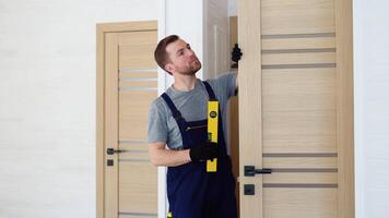 Male carpenter installing interior wood door with level in wooden prefabricated house video