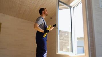 Worker measures of the vertical deviation of pvc windows in new wooden hotel room video