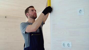 constructeur les mesures de le verticale déviation de le mur dans en bois préfabriqué maison. bulle niveau règle proche en haut voir, mesure et nivellement concept video