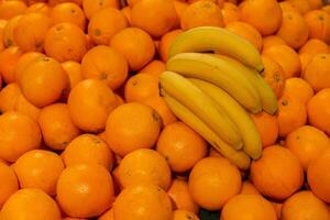 Branch of yellow ripe bananas and orange.Tropical fruits on sale. photo