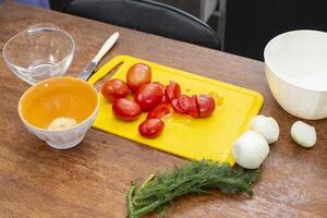 There is a cutting board with tomatoes and onions on the table. Prepare vegetable salad. photo