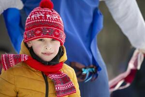 A child in winter clothes looks at the camera and smiles. photo