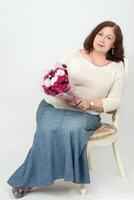 A beautiful elderly woman is holding a bouquet of flowers and is sad. photo