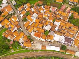 Bird's eye view from drone of a railroad track between residential areas and rice fields in Cicalengka, Indonesia. Shot from a drone flying 200 meters high photo