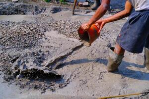 Industrial Photography. Construction work activities. Workers are hoeing and mixing cement with sand and stones for cement castings. Bandung - Indonesia, Asia photo