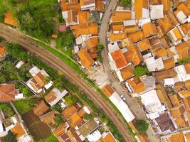 Bird's eye view from drone of a railroad track between residential areas and rice fields in Cicalengka, Indonesia. Shot from a drone flying 200 meters high photo