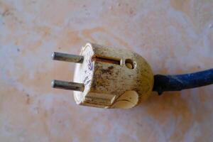 Industrial Photography. Construction Tools. Isolated worn electric plug with blue wire. A cable plug on the floor. Bandung, Indonesia photo