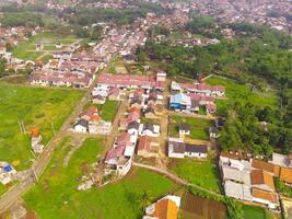 Aerial View of Nagreg City - Indonesia from the Sky. There are rice fields, valleys and hills, squeezed by dense settlements and a main road. Shot from a drone flying 200 meters high. photo