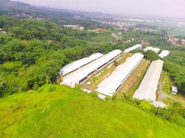 Top view of Corn storage and processing warehouse. Landscape view of the warehouse in the middle of expanse of trees and plantations. Aerial photography. Food industry. Shot from a flying drone photo