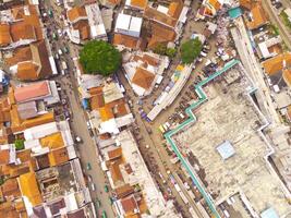 Aerial view of Main street of West Java Province, Indonesia. The main road in the middle of residential areas. Motorbikes, cars and electric vehicles traffic on the main road. Shot from a drone flying photo