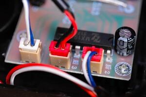 Macrophotography. Electrical closeup. Close up shot of the electrical circuit in an RC Remote Control Car. Background texture of PCB boards, cables, sockets and electronic devices. Shot with a macro photo