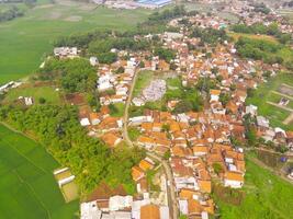 Aerial View of Nagreg City - Indonesia from the Sky. There are rice fields, valleys and hills, squeezed by dense settlements and a main road. Shot from a drone flying 200 meters high. photo