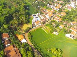 pájaro ojo ver de pueblo entre arroz campos en Bandung ciudad, Indonesia. paisaje de tierras de cultivo con arroz terraza agrícola cultivos en campo. agrícola campo. arriba. Disparo desde un zumbido volador foto