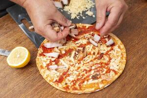 Man's hands add pieces of bacon to pizza. photo