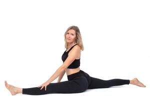A beautiful adult woman in sportswear does the splits. Stretching and flexible body in an older woman. photo