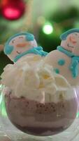 a cup of cocoa with cream two meringue snowmen macaroons on the background of a Christmas tree Christmas celebration glass glass beautiful tasty atmospheric background place for advertising video