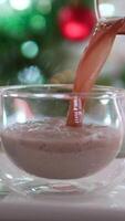 banana milk banana puree pour into a glass cup a delicious treat add cocoa and cream for New Year's Eve a delicious dessert with a Christmas tree in background lactose-free milk cow milk substitute video