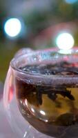 Chestnut brown tea in a transparent cup on a green summer bokeh background. Medicinal tincture from chestnut leaves. Healing infusion drink video