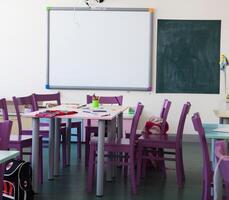 un salón de clases con púrpura sillas y un pizarra en el pared. foto