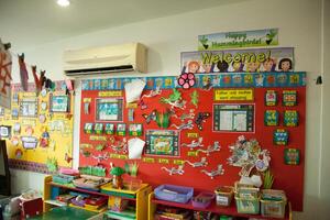 interior de un salón de clases con vistoso mesas y sillas con un pared colgando encima él, un colegio almacenamiento gabinete foto