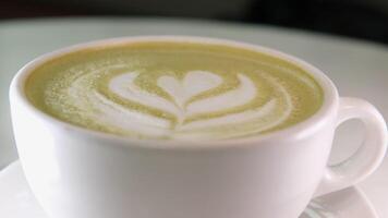 matcha beber dentro uma branco copo fechar-se desenhando em verde chá com leite lindo servindo dentro uma restaurante jantar amanhã. dieta video