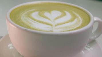 matcha bebida en un blanco taza de cerca dibujo en verde té con Leche hermosa servicio en un restaurante cena mañana. dieta video