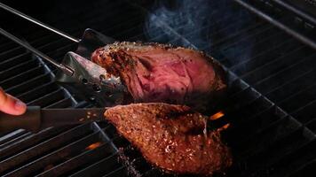 Koken steaks Aan de brand in echt detailopname visie van sappig gekookt plakjes van vlees met vlammen. origineel schotel recept. professioneel Koken, voedsel recept, Koken. horizontaal . top visie. video