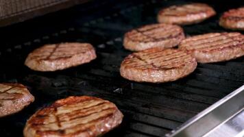 kock matlagning utegrill scen hamburgare vänt över med en tong spatel svarvare på de grill över en lugna brand flamma video