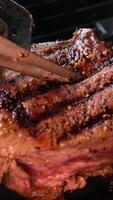 Panarama close-up of a juicy piece of steak being turned over in a hot skillet video