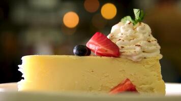 Strawberry cheesecake served on plate on dim wooden table foundation. video