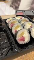 Sushi entrega conjunto Sushi en el plastico contenedores en real vida de cerca California rollos con volador pescado caviar comida entrega a tu hogar video
