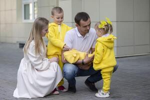 Mom and dad show the children a newborn baby. A baby has appeared in the family. Meeting your newborn brother or sister. Family with children at the maternity hospital. photo