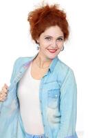 Portrait of a beautiful cheerful redhead girl in a denim shirt, smiling and laughing, looking at the camera on a white background. photo