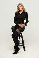 Beautiful middle-aged blonde woman in black clothes posing in the studio photo