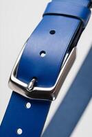 Part of a blue leather classic belt with a buckle on a gray background. photo