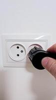 Electrical plug in the socket to protect children from electric shock, close-up. A man's hand plugs a plug into an electrical socket video