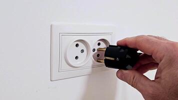 Electrical plug in the socket to protect children from electric shock, close-up. A man's hand plugs a plug into an electrical socket video