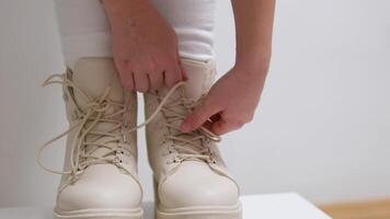 close-up. a little girl puts on her lace-up winter boots. the concept of children's independence and the ability to tie shoelaces. video