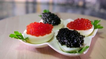 Preto e vermelho peixe ovas caviar servido em fervido ovos ovos com vermelho caviar em uma prato servindo restaurante video