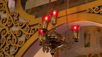 närbild av skön dekorativ röd ljus hängande på kedjor i de kyrka video