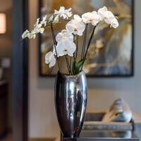 A sleek metal vase displays a group of elegant orchids. photo